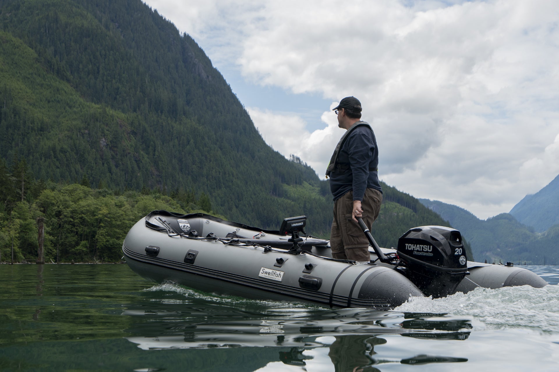 A man standing on a Swellfish Classic as he moves across the lake shows how stable the boat is.